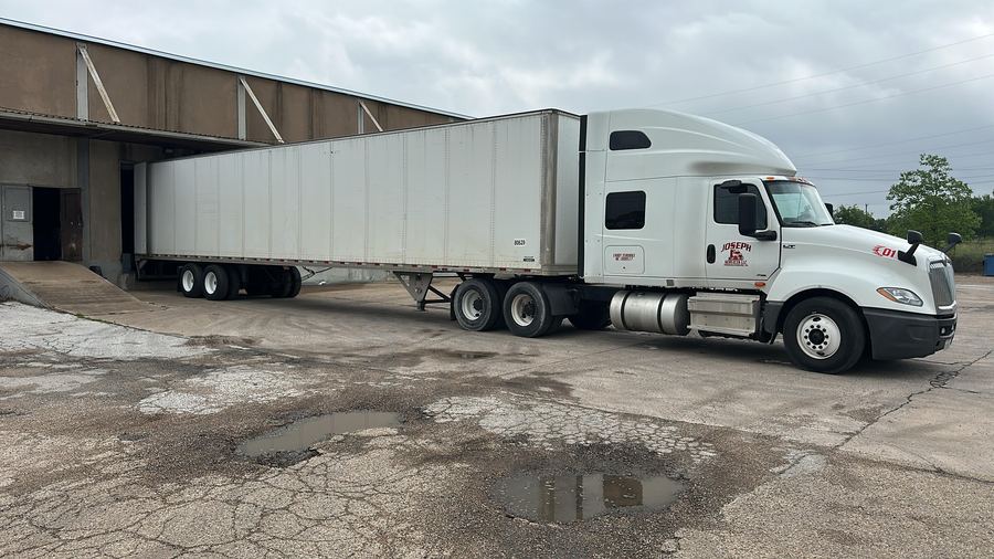 A Joseph Services tractor coupled to a dry van at a warehouse loading dock