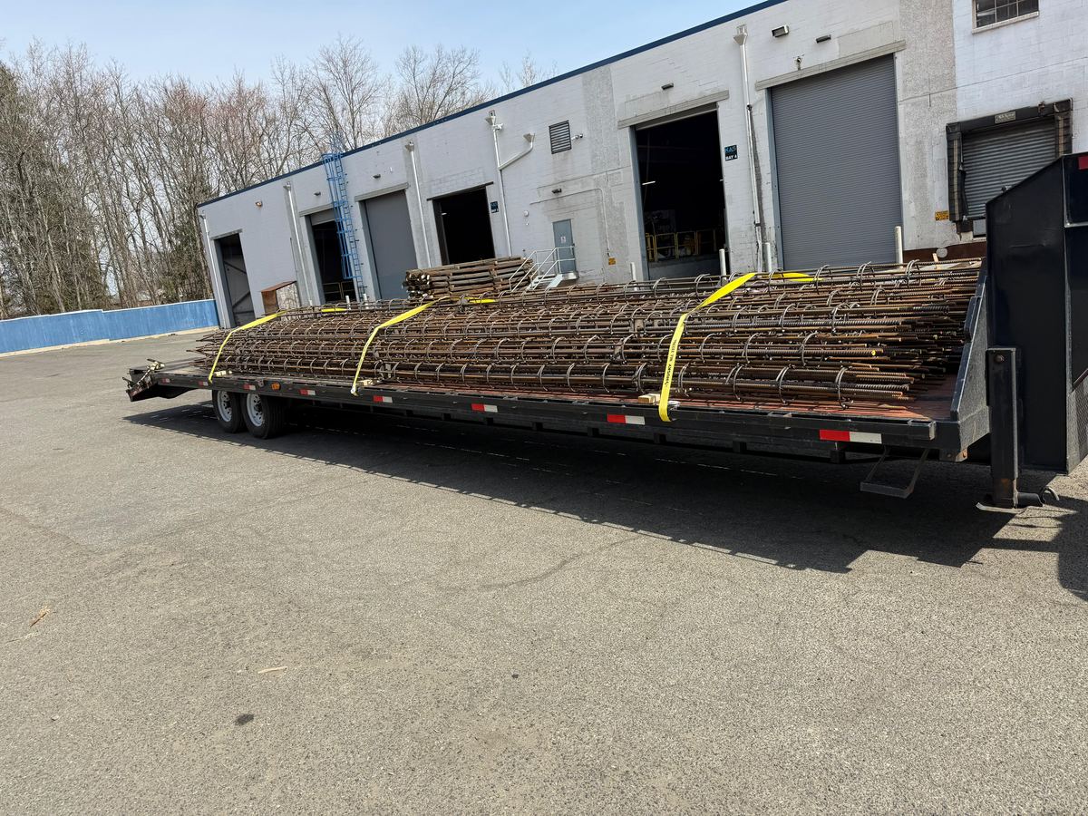 Bundled steel strapped to a flatbed backed up to a loading dock